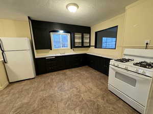 Kitchen featuring a healthy amount of sunlight, sink, white appliances, and a textured ceiling