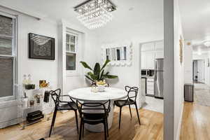 Dining space with light hardwood / wood-style flooring, a chandelier, and ornamental molding