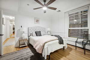 Bedroom with ceiling fan, crown molding, and wood-type flooring