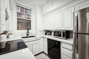 Kitchen featuring white cabinets, light stone counters, sink, and stainless steel appliances