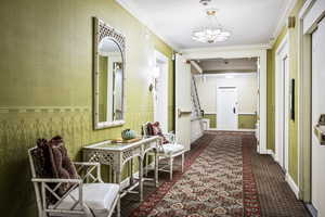 Hall with dark colored carpet and ornamental molding