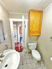 Bathroom featuring a textured ceiling, ornamental molding, and sink