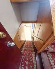 Stairway with hardwood / wood-style floors and wooden walls