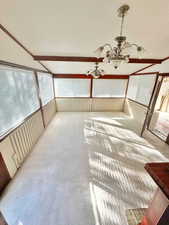 Unfurnished sunroom featuring a notable chandelier