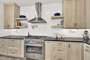 Kitchen featuring stainless steel range, backsplash, and wall chimney range hood