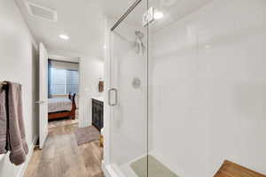 Bathroom with hardwood / wood-style flooring and a shower with shower door