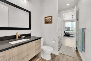 Bathroom with hardwood / wood-style floors, vanity, and toilet