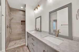 Bathroom with hardwood / wood-style flooring, vanity, and a tile shower