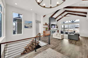 Living room featuring a wealth of natural light, beamed ceiling, hardwood / wood-style flooring, and an inviting chandelier