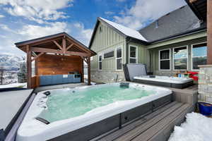 Snow covered deck featuring a covered hot tub and a mountain view