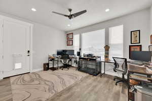 Office space featuring ceiling fan, light wood-type flooring, and a textured ceiling