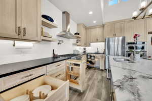 Kitchen with sink, stainless steel appliances, range hood, light brown cabinetry, and light wood-type flooring