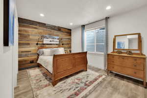 Bedroom featuring light wood-type flooring and wooden walls