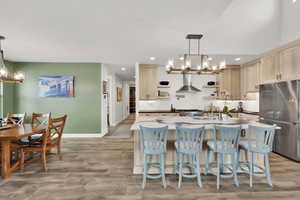 Kitchen with stainless steel fridge, light wood-type flooring, a notable chandelier, and pendant lighting