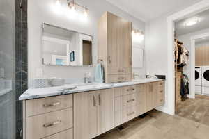 Bathroom with washer and dryer, vanity, and hardwood / wood-style flooring