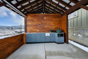 Snow covered patio featuring a mountain view, sink, and an outdoor kitchen