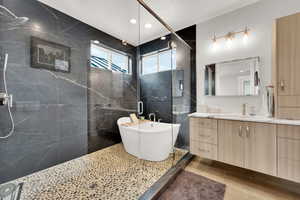 Bathroom with a textured ceiling, vanity, plus walk in shower, and tile walls