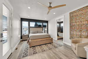 Bedroom featuring a textured ceiling, light wood-type flooring, ceiling fan, and connected bathroom