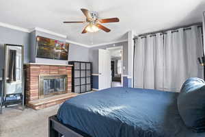 Bedroom with light carpet, a fireplace, ceiling fan, and crown molding