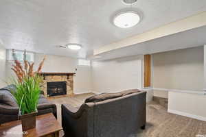 Carpeted living room featuring a fireplace and a textured ceiling