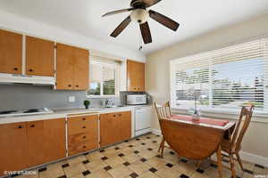 Kitchen featuring backsplash, ceiling fan, sink, and white appliances