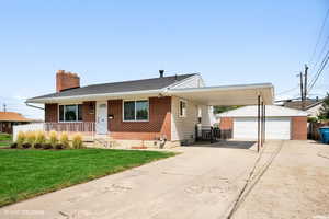 View of front facade featuring a carport, a garage, an outdoor structure, and a front lawn