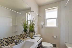 Full bathroom with vanity, toilet, backsplash, and tiled shower / bath combo