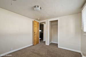 Unfurnished bedroom with carpet floors, a textured ceiling, and a closet