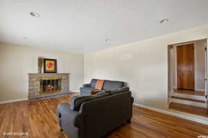 Living room with a stone fireplace and hardwood / wood-style flooring