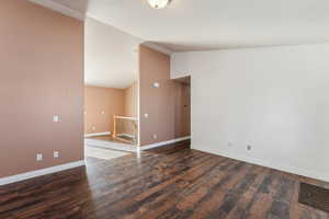 Spare room featuring vaulted ceiling and dark hardwood / wood-style floors