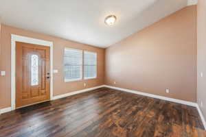 Foyer featuring dark hardwood / wood-style flooring and vaulted ceiling