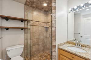 Bathroom featuring a shower with door, vanity, and toilet