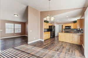 Kitchen with tasteful backsplash, dark hardwood / wood-style floors, black appliances, and vaulted ceiling