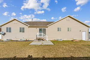 Rear view of property with a lawn and a patio area