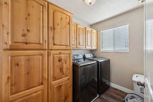 Washroom featuring cabinets, washing machine and dryer, and dark hardwood / wood-style floors