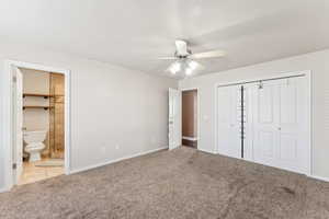 Unfurnished bedroom with connected bathroom, ceiling fan, a closet, and light colored carpet