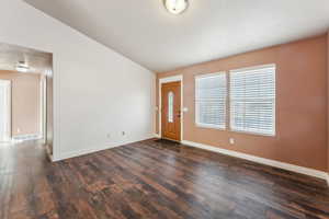 Entrance foyer with dark hardwood / wood-style flooring and lofted ceiling