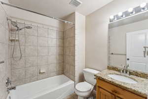 Full bathroom featuring tile patterned floors, tiled shower / bath combo, toilet, and vanity