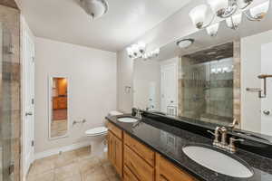 Bathroom featuring a notable chandelier, tile patterned floors, toilet, vanity, and a shower with shower door