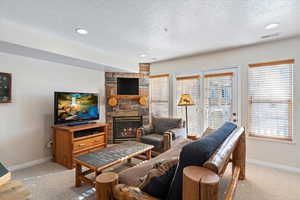 Carpeted living room with a fireplace and a textured ceiling