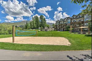 View of property's community with a lawn, a mountain view, and volleyball court