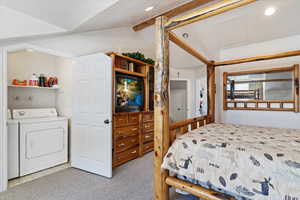 Bedroom featuring light carpet, a textured ceiling, lofted ceiling with beams, and washing machine and clothes dryer