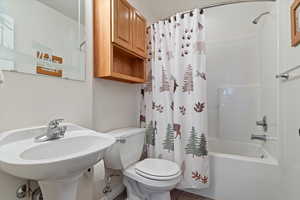 Full bathroom with tile patterned flooring, shower / bath combination with curtain, toilet, and sink