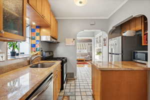 Kitchen featuring appliances with stainless steel finishes, a healthy amount of sunlight, crown molding, and sink