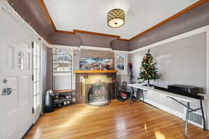 Living room featuring crown molding, a fireplace, a healthy amount of sunlight, and hardwood / wood-style flooring