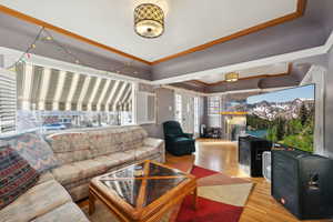 Living room featuring light hardwood / wood-style floors, a brick fireplace, and crown molding