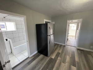 Kitchen with a textured ceiling, stainless steel fridge, white cabinets, and dark hardwood / wood-style floors