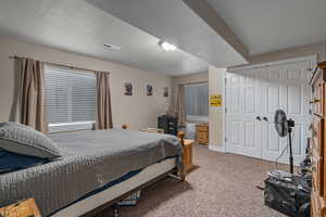 Bedroom with carpet, a textured ceiling, and a closet