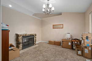 Living room featuring an inviting chandelier, light colored carpet, vaulted ceiling, and crown molding