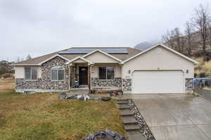 Ranch-style home featuring solar panels, a porch, a garage, and a front lawn